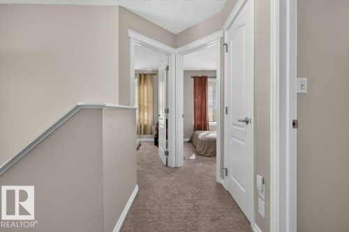 Carpeted hallway with light neutral wall paint and white trim - 692 Secord Boulevard Nw, Edmonton, AB - Indoor Photo Showing Other Room