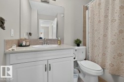 Bathroom vanity with a light-colored countertop, integrated sink, and white cabinetry featuring black hardware - 