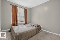 Carpeted room with a window featuring horizontal blinds and decorative curtain rods - 