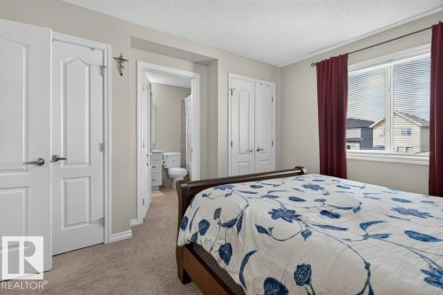 Carpeted bedroom featuring a large window with blinds, white trim, and a double-door closet - 692 Secord Boulevard Nw, Edmonton, AB - Indoor Photo Showing Bedroom