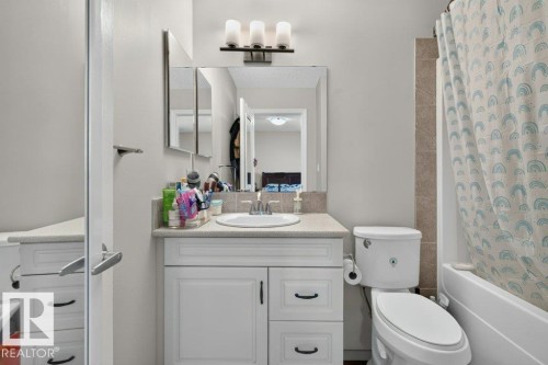 Bathroom featuring a white vanity with built-in storage, a basin sink with a chrome faucet, and a wall-mounted medicine cabinet with integrated lighting - 692 Secord Boulevard Nw, Edmonton, AB - Indoor Photo Showing Bathroom