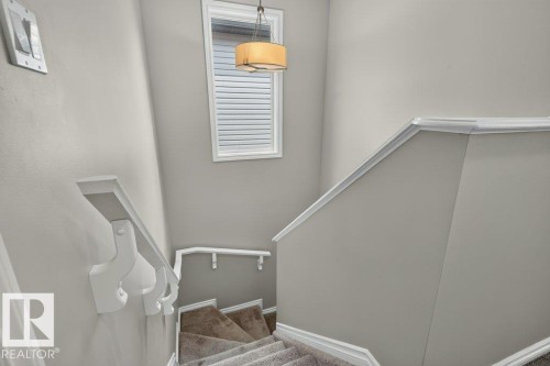 Carpeted stairway with white painted handrails and trim - 692 Secord Boulevard Nw, Edmonton, AB - Indoor Photo Showing Other Room