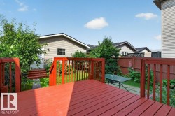 Spacious red-stained wooden deck overlooking a private backyard - 