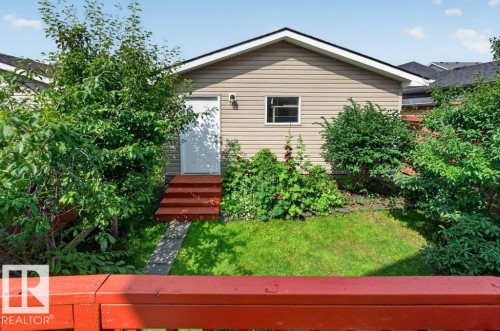Rear exterior featuring horizontal siding, a white entry door with red-painted steps, and a single pane window - 692 Secord Boulevard Nw, Edmonton, AB - Outdoor