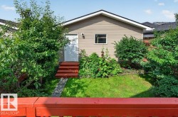 Rear exterior featuring horizontal siding, a white entry door with red-painted steps, and a single pane window - 