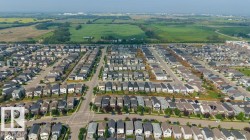 Aerial perspective of a developed residential area featuring numerous single-family homes, paved streets, and green spaces - 