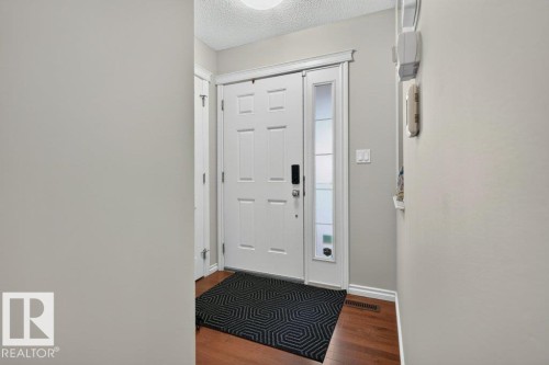 Entryway featuring a white paneled door with a smart lock, sidelight, and wood-finish flooring - 692 Secord Boulevard Nw, Edmonton, AB - Indoor Photo Showing Other Room