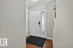 Entryway featuring a white paneled door with a smart lock, sidelight, and wood-finish flooring - 