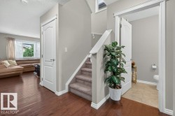 Hardwood-finish flooring extending into the main living area, complemented by a carpeted staircase with white risers and handrail - 