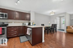 Kitchen with wood-finish flooring, dark wood cabinetry, stainless steel appliances, and light-toned countertops - 