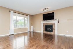 Hardwood flooring throughout featuring a gas fireplace with a stone surround and white mantel - 