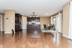 Open-concept kitchen and dining area featuring rich wood-finish flooring - 
