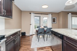 Kitchen area featuring dark wood-finish cabinetry and light-toned, speckled countertops - 