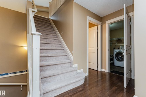 Curved staircase with carpeted treads and white wood balustrade - 2605 Anderson Crescent Sw, Edmonton, AB - Indoor Photo Showing Other Room
