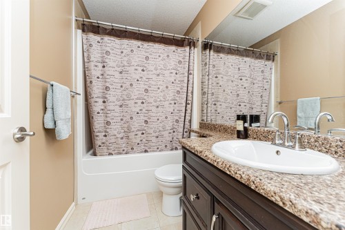 Bathroom featuring a dark wood-finish vanity with an integrated sink, a speckled countertop, and a large wall-mounted mirror - 2605 Anderson Crescent Sw, Edmonton, AB - Indoor Photo Showing Bathroom