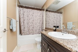 Bathroom featuring a dark wood-finish vanity with an integrated sink, a speckled countertop, and a large wall-mounted mirror - 