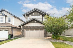 Contemporary two-story exterior featuring a double-car garage with paneling, stone facade accents, light-toned siding, dark trim, and multiple windows - 