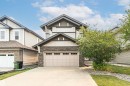 Contemporary two-story exterior featuring a double-car garage with paneling, stone facade accents, light-toned siding, dark trim, and multiple windows - 2605 Anderson Crescent Sw, Edmonton, AB  - Outdoor 
