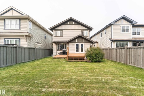 Expansive rear yard featuring a manicured lawn, a sizable wooden deck with steps, and a decorative shrub - 2605 Anderson Crescent Sw, Edmonton, AB - Outdoor