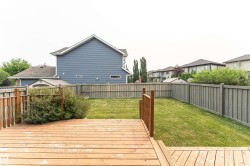 Spacious backyard featuring a multi-level wood deck with railing, a manicured lawn, and perimeter wood fencing - 
