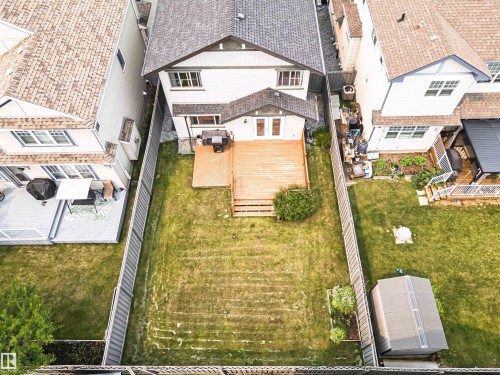 Expansive backyard featuring a large wooden deck, dual French doors, a manicured lawn, and a storage shed - 2605 Anderson Crescent Sw, Edmonton, AB - Outdoor