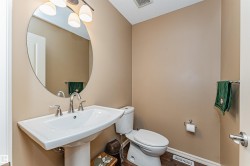Pedestal sink with chrome fixtures and an oval mirror, complemented by an overhead light fixture - 