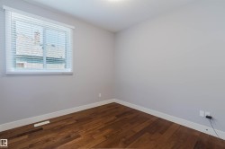 Room featuring wood-finish flooring, light grey painted walls, and white baseboards - 