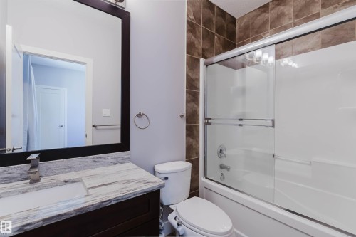 Bathroom featuring a dark wood-finish vanity with a light-toned patterned countertop, an undermount rectangular sink, and a brushed nickel faucet - 10626 81 Avenue Nw, Edmonton, AB - Indoor Photo Showing Bathroom