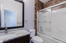 Bathroom featuring a dark wood-finish vanity with a light-toned patterned countertop, an undermount rectangular sink, and a brushed nickel faucet - 