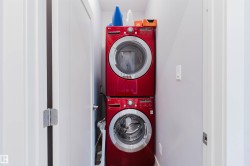 Dedicated laundry area featuring a stacked, front-loading washer and dryer set - 