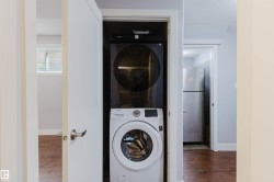 Stacked front-loading washer and dryer in a dedicated closet, featuring a white door with a lever handle - 
