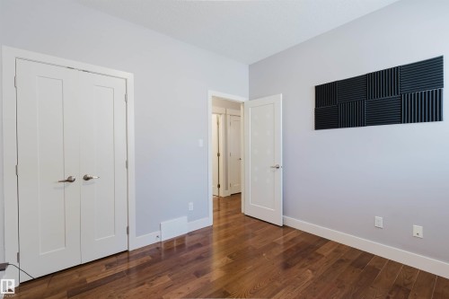 Hardwood-style flooring throughout this room, featuring light gray walls, white trim, and white interior doors - 10626 81 Avenue Nw, Edmonton, AB - Indoor Photo Showing Other Room