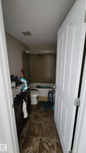 Bathroom featuring dark wood-finish vanity with countertop, white toilet, and tile flooring - #415 12045 22 Av Sw, Edmonton, AB - Indoor Photo Showing Bathroom