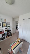 Recessed lighting fixture illuminating a room with white walls, textured ceiling, and carpet flooring - 