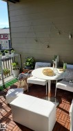 Balcony featuring wood-finish floor tiles, a painted horizontal siding wall, and a black metal railing - 
