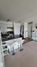 Kitchen featuring white cabinetry, black countertops, a stainless steel sink, and a white subway tile backsplash - #415 12045 22 Av Sw, Edmonton, AB  - Indoor 