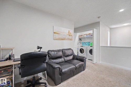 Carpeted room featuring a built-in laundry closet with bi-fold doors, upper shelving, and full-size appliances - 22419 80 Avenue Nw, Edmonton, AB - Indoor