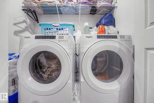 Laundry area featuring a side-by-side washer and dryer, an overhead wire shelving unit, and a white paneled door - 22419 80 Avenue Nw, Edmonton, AB - Indoor Photo Showing Laundry Room