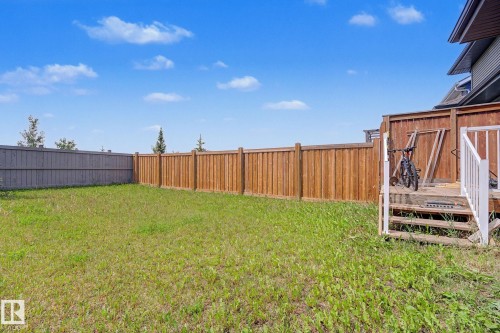 Expansive backyard featuring a manicured lawn, a wooden fence, and a multi-level wooden deck with white railings - 22419 80 Avenue Nw, Edmonton, AB - Outdoor