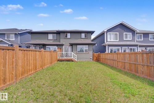 Expansive fenced backyard featuring a wooden privacy fence, a wooden deck with white railings, and a grass lawn - 22419 80 Avenue Nw, Edmonton, AB - Outdoor