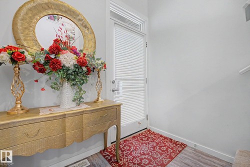 Entryway featuring a white door with a privacy blind, light wood-finish flooring, and a portion of a staircase with a white railing - 22419 80 Avenue Nw, Edmonton, AB - Indoor Photo Showing Other Room