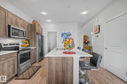 Kitchen featuring an island with seating, stainless steel appliances, wood-finish flooring, recessed lighting, and light-toned cabinetry - 22419 80 Avenue Nw, Edmonton, AB - Indoor Photo Showing Kitchen