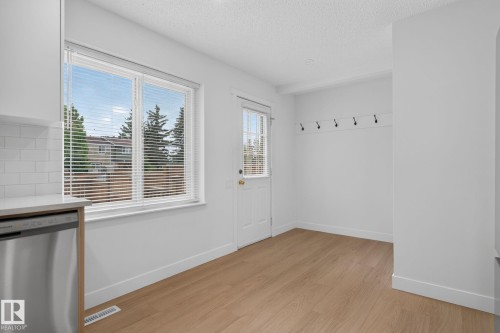 Bright dining area featuring wood-finish flooring and a rear door with a full-light panel - 8059 178 Street Nw, Edmonton, AB - Indoor Photo Showing Other Room