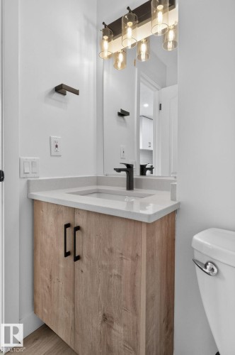 Modern vanity featuring a wood-finish cabinet, light countertop, and matte black hardware - 8059 178 Street Nw, Edmonton, AB - Indoor Photo Showing Bathroom