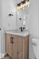 Modern vanity featuring a wood-finish cabinet, light countertop, and matte black hardware - 