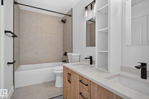 Modern bathroom featuring a dual vanity with light wood-finish cabinetry, integrated sinks, and matte black fixtures - 8059 178 Street Nw, Edmonton, AB - Indoor Photo Showing Bathroom