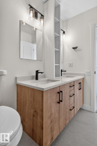 Double vanity featuring wood-finish cabinetry, white countertops, and dual undermount sinks - 8059 178 Street Nw, Edmonton, AB - Indoor Photo Showing Bathroom
