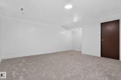 Spacious room featuring light-toned carpet flooring, white walls, and a contemporary flush-mount ceiling light - 