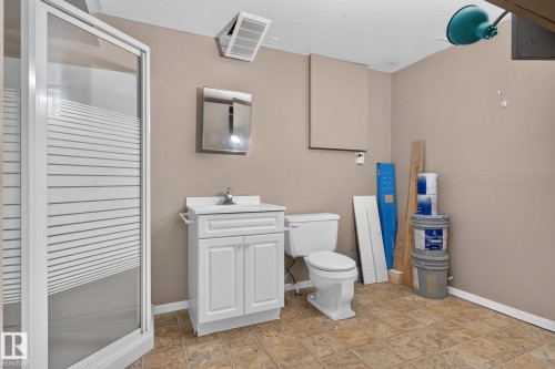 Bathroom featuring a stand-up shower with frosted glass, a white vanity with integrated sink, a toilet, and neutral-toned wall paint - 8059 178 Street Nw, Edmonton, AB - Indoor Photo Showing Bathroom