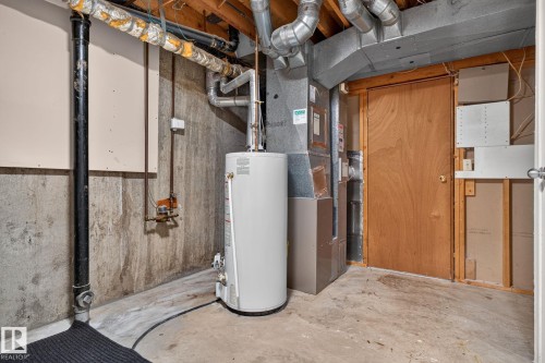 Utility area featuring a water heater, furnace system, exposed ceiling joists, and concrete flooring - 8059 178 Street Nw, Edmonton, AB - Indoor Photo Showing Basement